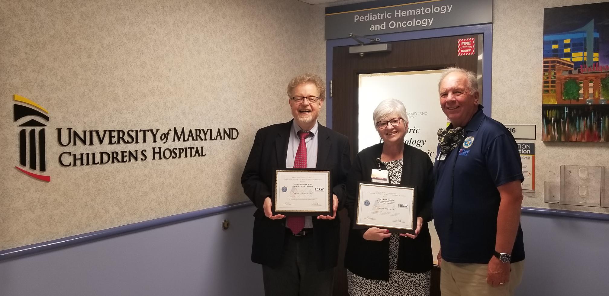 Steven J. Czinn and Mary Beth Lamon hold up Patriot awards received from Michael Comeau